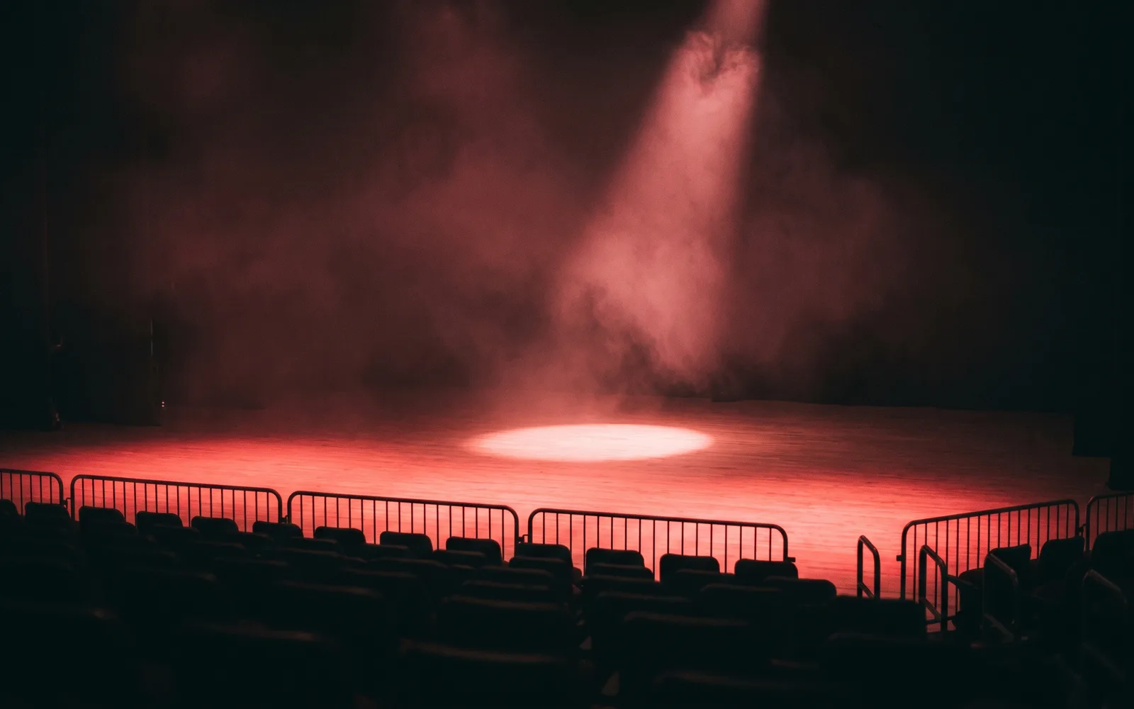 Speaker on a dark stage under a single red-lit spotlight